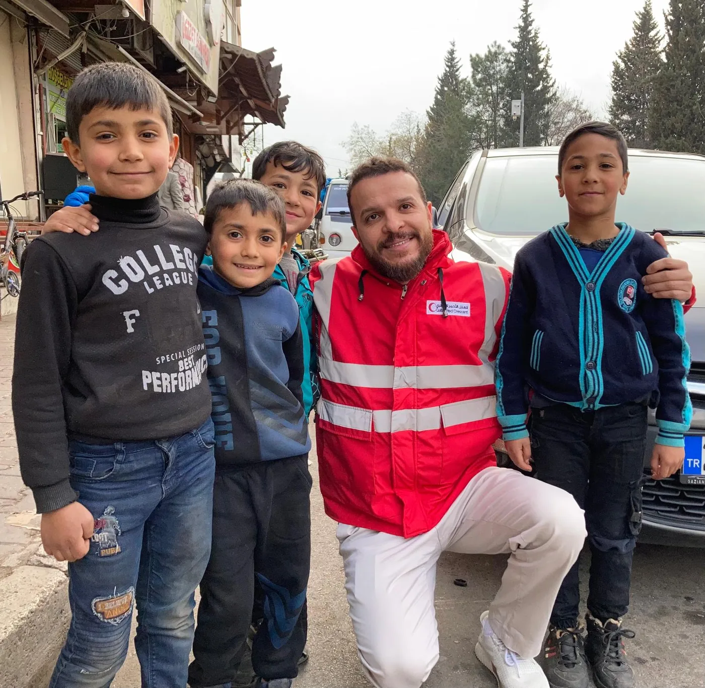 Mohammed Mansour kneeling beside smiling children during a relief campaign