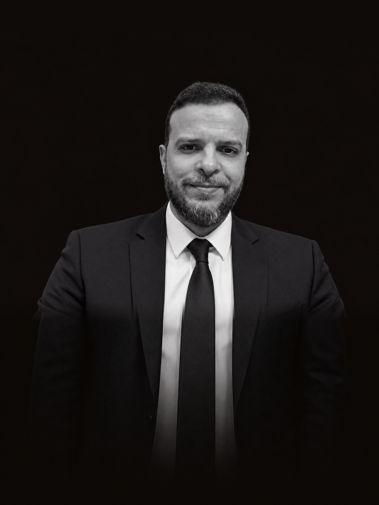 Frontal black-and-white portrait of Mohammed Mansour in a dark suit
